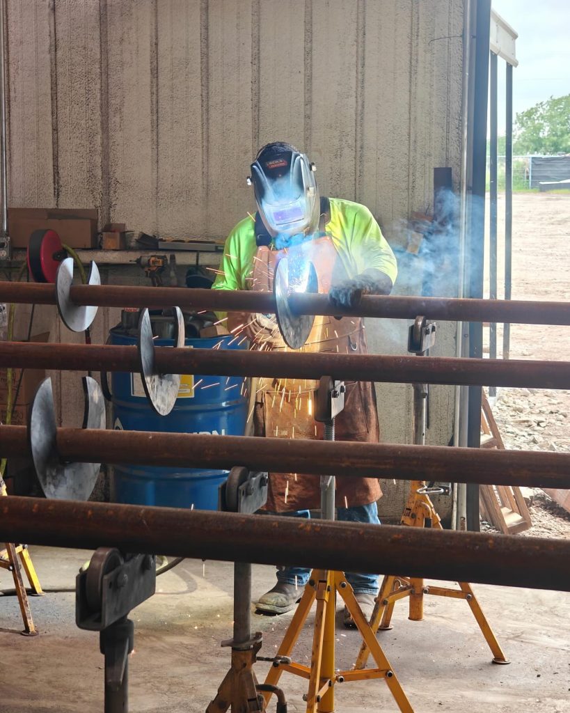 FnD Piers Team member welding together several helical piers
