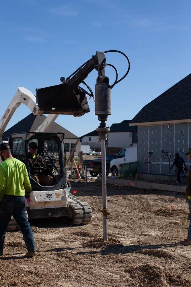 Construction workers installing helical piers.