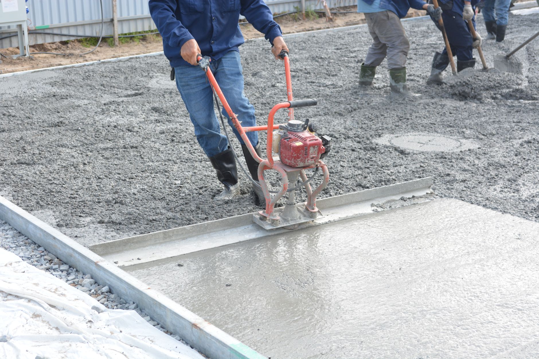 Crew leveling and smoothing a freshly poured concrete slab