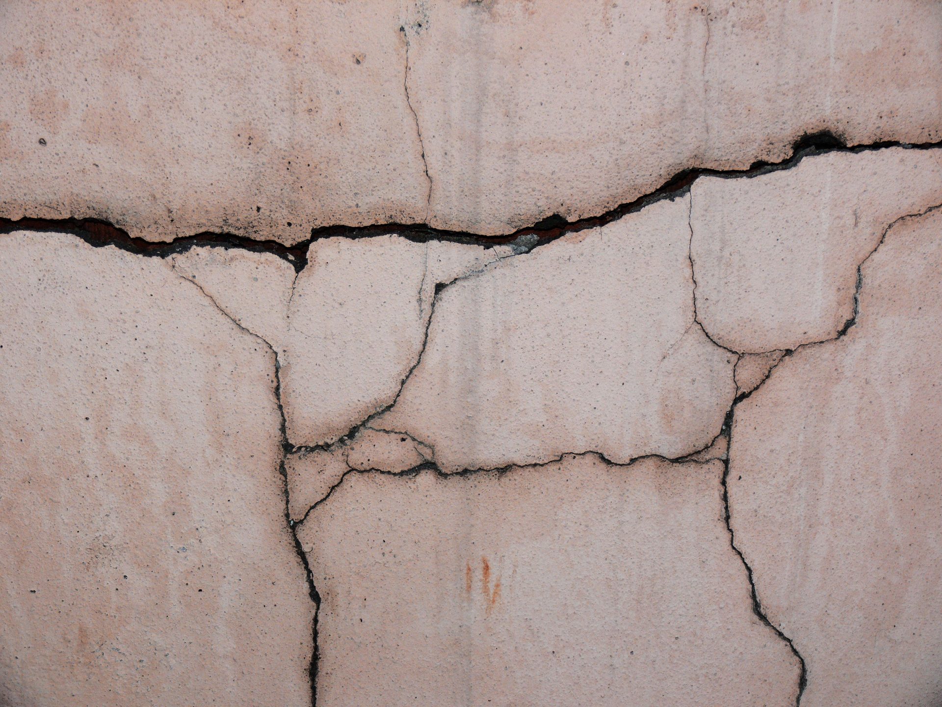 Prominent structural cracks in a building's concrete wall — a sign of foundation problems