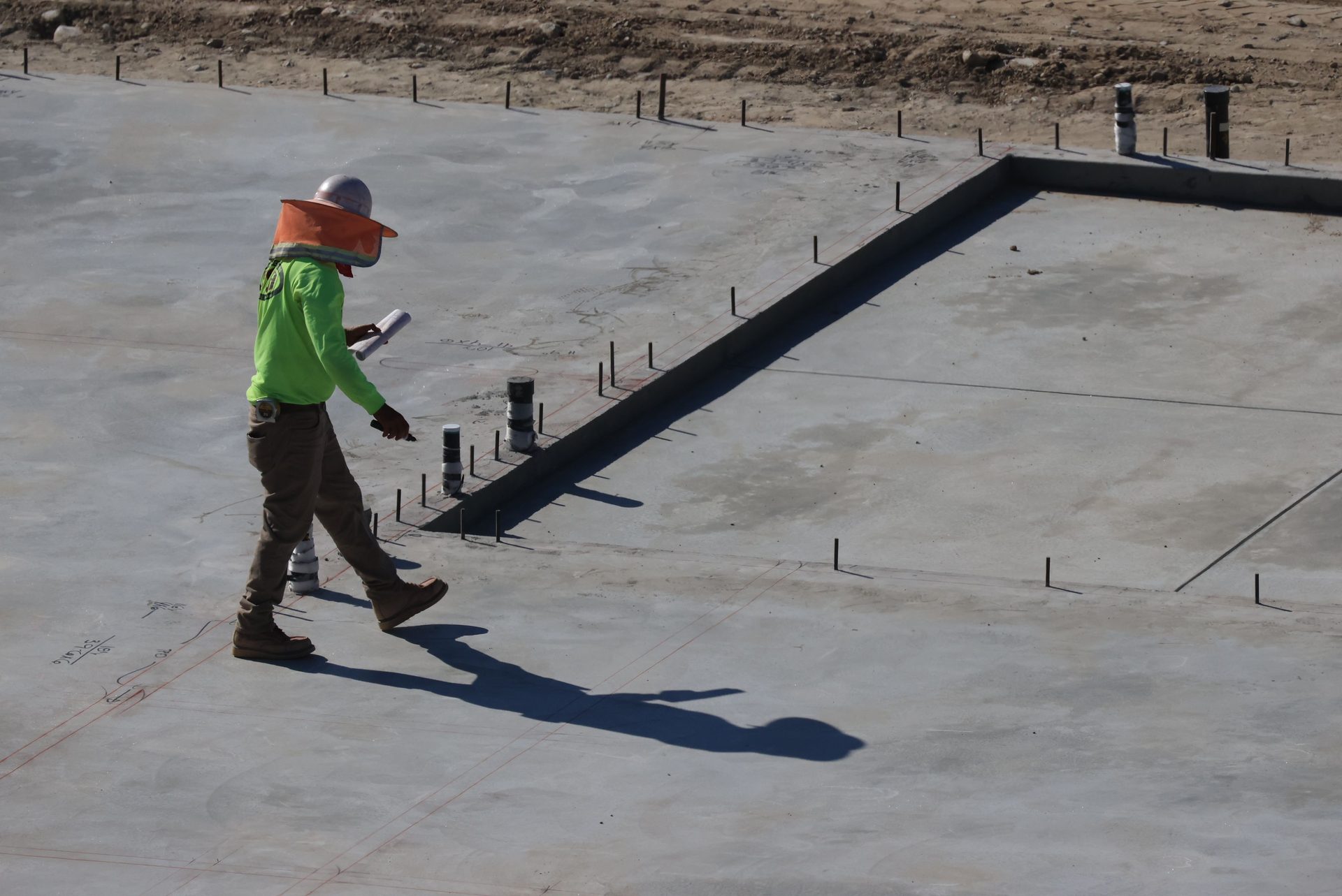 Inspector surveying a concrete foundation slab for level and settlement
