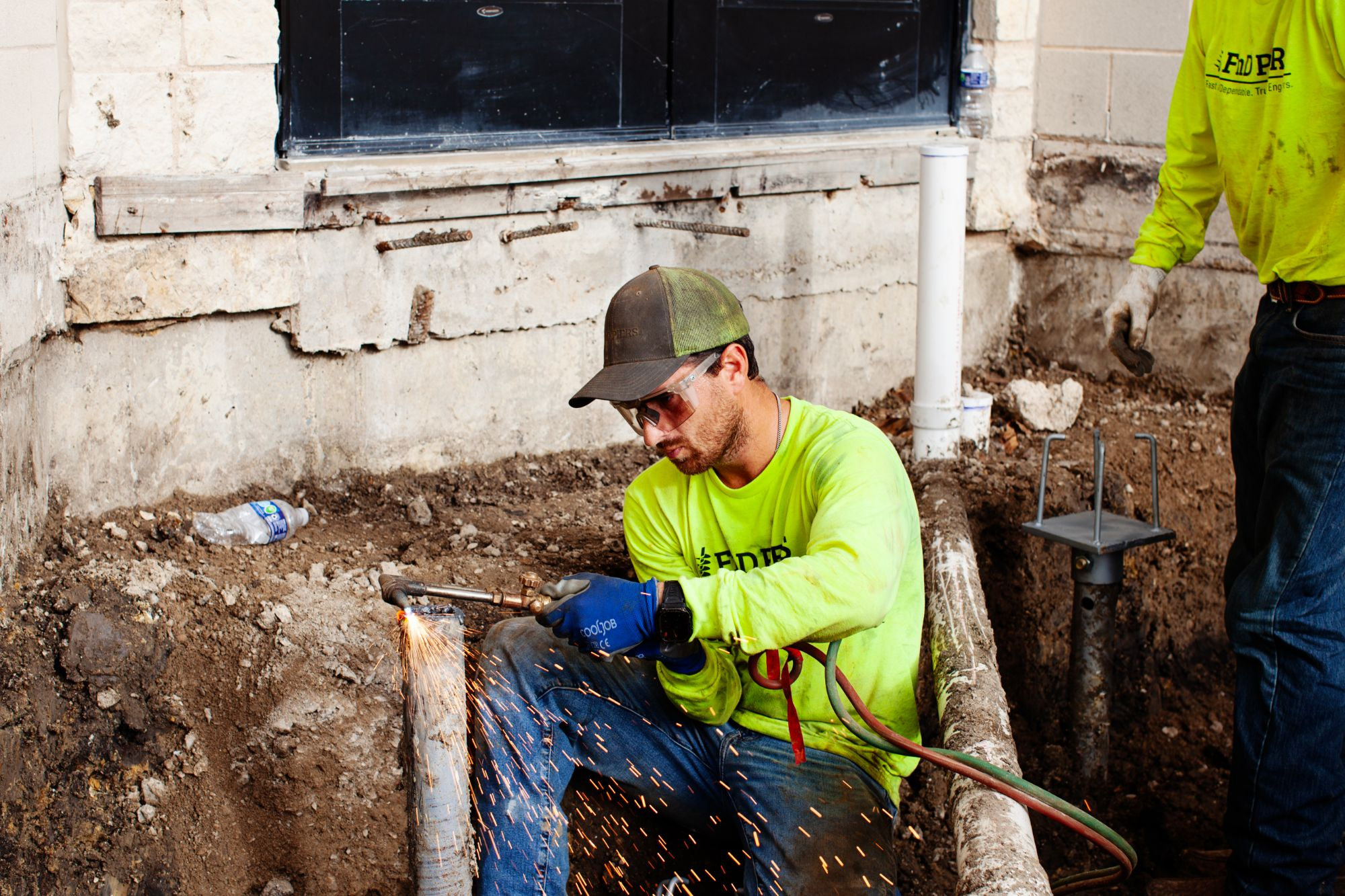 FnD Piers technician welding a helical pier bracket during foundation repair, serving Eagle Mountain, TX