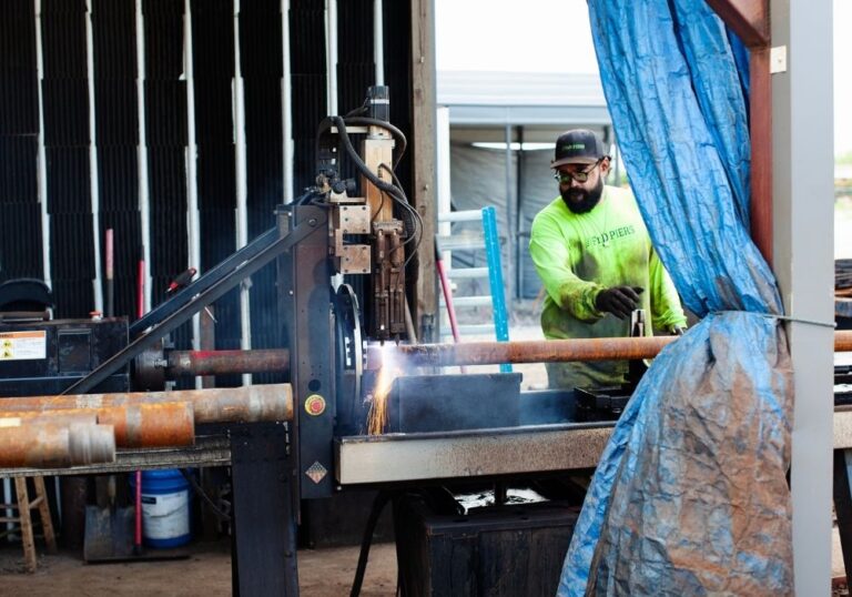 Man welding metal pipes in workshop