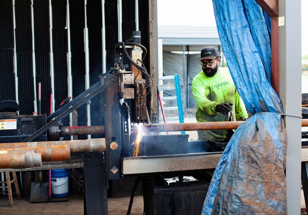 Man welding metal pipes in workshop